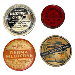 May include: Four vintage ointment tins. The tins are round with labels in various colors. One tin reads "Black and White Ointment", another "Derma Medicone", a third "Charles May & Son", and the last "Vicks Vaporub".