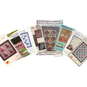 May include: A collection of eight quilting patterns featuring various designs, including "Belle of the Ball", "Strip Tube Chevron", "Stacked Mariner's Compass", "Boxops Op", "Butterfly Basket", and "Piece by Piece Quilts".