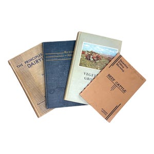 May include: Four vintage books with titles including "The Principles of Dairy," "Vegetable Growing," and "Beef Cattle." The books have various colors, including tan, blue, and light green. The "Beef Cattle" book is a light brown color.