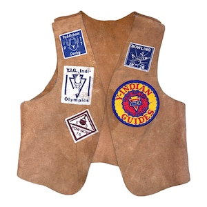 May include: A brown leather vest with various patches, including "Paddleboat Derby 9 7", "Y.I.G. Indi Olympics", "POW WOW 76", "Bowling 19 76", and "Indian Guides".