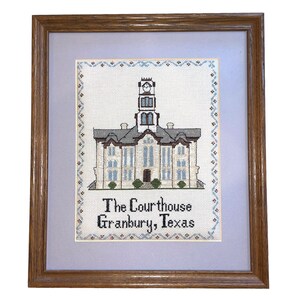 May include: A framed cross-stitch embroidery depicting a courthouse building with a clock tower. The text below the building reads "The Courthouse Granbury, Texas".
