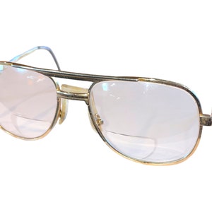 May include: Gold-tone aviator style eyeglasses with clear lenses.