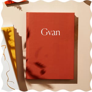 May include: A red hardcover journal with the word "Gvan" printed in white on the front cover.
