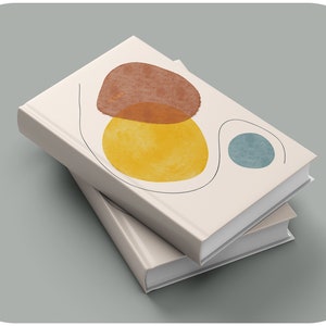 May include: Two white hardcover books stacked on top of each other. The top book has a minimalist design with abstract shapes in shades of brown, yellow, and blue.