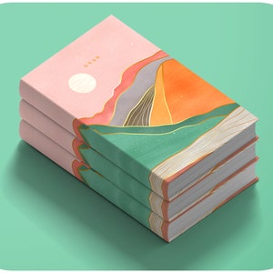 May include: A stack of three hardcover books with a colorful abstract design featuring mountains, a sun, and gold lines. The top book has the word "CYAN" printed on the cover.
