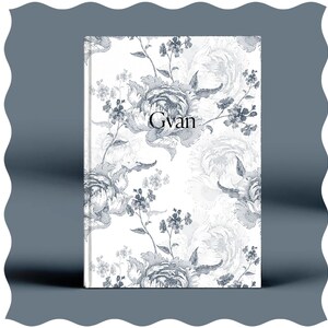 May include: A white journal with a floral pattern in shades of grey. The word "Gvan" is printed in black on the front cover.