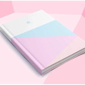 May include: A pink, white and light blue notebook with a geometric design. The notebook has a white spine and a small sun symbol on the front cover.