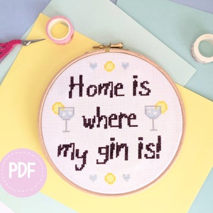 May include: A white embroidery hoop with a black and white cross-stitch design that says "Home is where my gin is!" with two yellow lemons and two blue martini glasses.