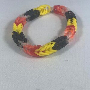 May include: A colorful rubber band bracelet with black, yellow, red, and clear bands.