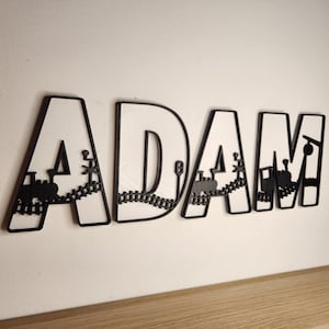 May include: Black wooden letters spelling the name "ADAM" with a train and track design cut out of the letters.