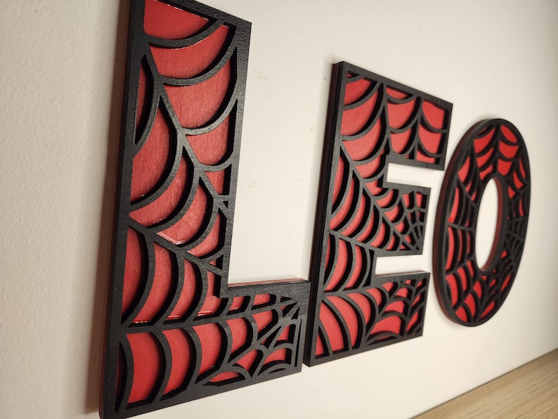 May include: Black and red wooden letters spelling out the name "LEO" with a spiderweb design.
