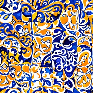 Op de afbeelding: Een close-up van een patchwork van keramische tegels. Elke tegel heeft een uniek, sierlijk ontwerp in tinten blauw, oranje en wit. De patronen omvatten wervelende bloemmotieven en gestileerde vormen.