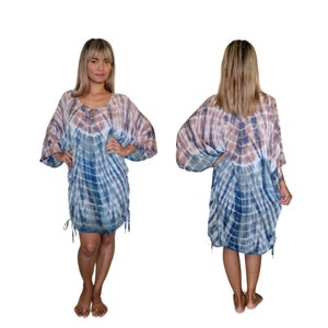 May include: A tie-dye dress in shades of blue, brown, and white. The dress has a loose, flowing design with wide sleeves and drawstring details at the sides. The model is wearing the dress, with front and back views.