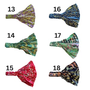 Pu&ograve; includere: Una collezione di sei fasce per capelli in tessuto in vari colori e fantasie. Le fasce presentano un design ampio e annodato. I colori includono verde, blu, rosso e nero, con stampe floreali e astratte. Ogni fascia &egrave; numerata.