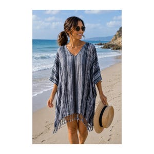 May include: A V-neck kaftan cover-up featuring a vertical striped pattern in shades of navy blue, white, and grey. The garment has short, wide sleeves and a hemline finished with decorative fringe tassels. A straw hat is held at the side.