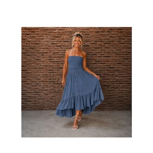 May include: A dusty blue strapless midi dress featuring a fitted bodice, a vertical row of buttons down the center front, and a ruffled high-low hemline. The garment is constructed with a simple silhouette and a solid color finish.