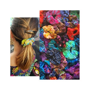 May include: A collection of colorful, patterned hair scrunchies. The scrunchies are made of fabric and have a variety of designs, including floral, geometric, and abstract patterns. The scrunchies are arranged in a pile, and some are overlapping.