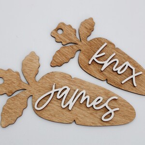 May include: Two wooden carrot-shaped ornaments with the names "James" and "Knox" written in white paint.