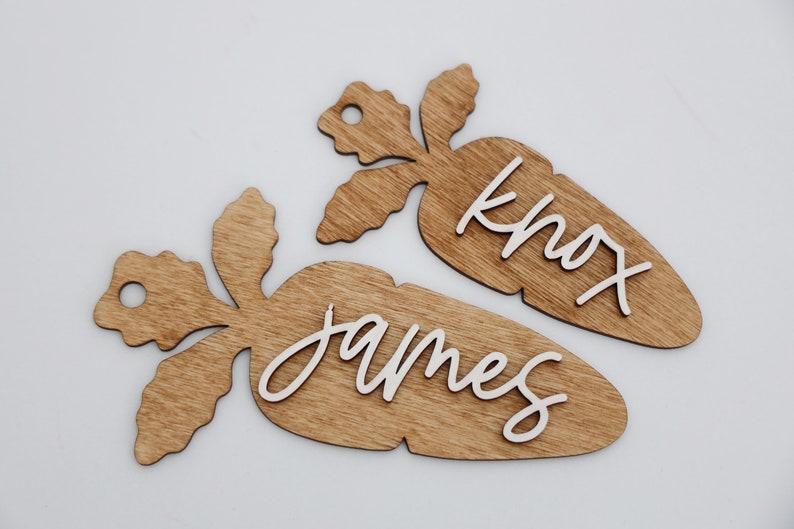 May include: Two wooden carrot-shaped ornaments with the names "James" and "Knox" written in white paint.