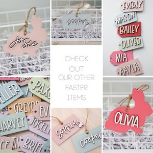 May include: A collection of wooden Easter bunny and tag ornaments with various names written on them. The ornaments are in a variety of colors, including pink, blue, green, and red. The text "CHECK OUT OUR OTHER EASTER ITEMS" is written in the center of the image.