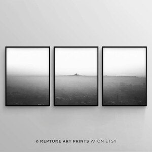 May include: A set of three black and white framed prints featuring a foggy landscape with a silhouette of a building in the distance.