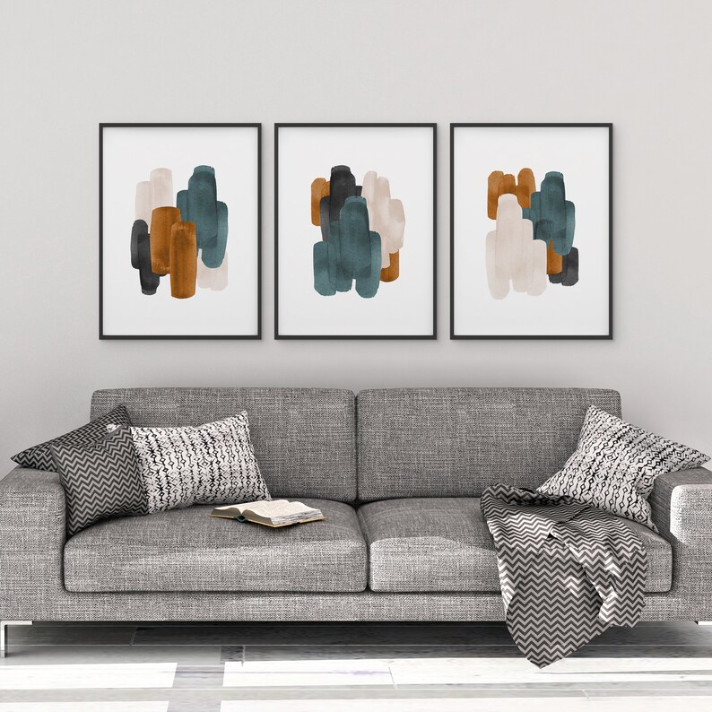 May include: Three framed abstract art prints with a gray background. The prints feature overlapping shapes in shades of teal, brown, and beige.