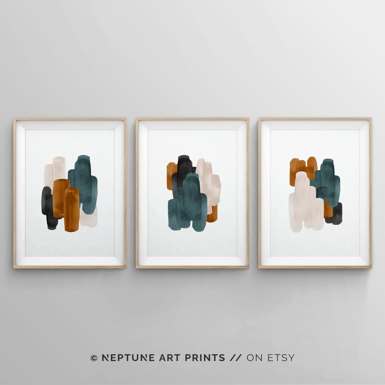 May include: Set of three abstract art prints featuring a minimalist design with geometric shapes in shades of teal, brown, and beige. The prints are framed in natural wood.