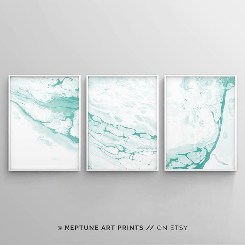 May include: Set of three abstract art prints featuring a white background with teal blue marbling. The prints are framed in white.