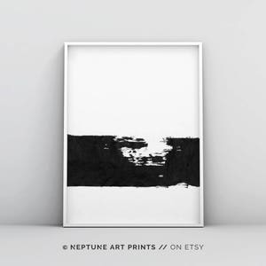 May include: Black and white abstract art print with a thick black brushstroke across the bottom half of the print. The print is framed in a white frame.