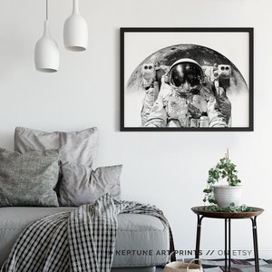 Peut inclure: Photographie en noir et blanc d'un astronaute en combinaison spatiale, avec la lune en arri&egrave;re-plan. L'astronaute regarde directement la cam&eacute;ra.