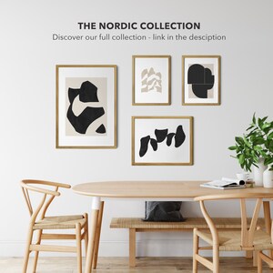 May include: Four framed abstract art prints with black and beige shapes on a white background. The prints are hanging on a white wall above a wooden table with two chairs.