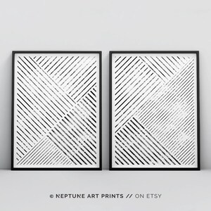 May include: Two black and white abstract geometric prints in black frames. The prints feature a pattern of diagonal lines and squares.