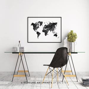 Peut inclure: Impression aquarelle de la carte du monde en noir et blanc dans un cadre noir accroch&eacute; &agrave; un mur blanc au-dessus d'un bureau en verre avec une chaise noire. Le bureau est sur un sol en bois.