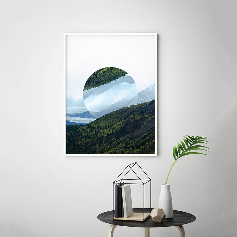 Peut inclure: Une impression encadr&eacute;e d'une photographie de paysage avec une d&eacute;coupe circulaire r&eacute;v&eacute;lant une cha&icirc;ne de montagnes et un ciel nuageux. Les montagnes sont vertes et le ciel est bleu et blanc.