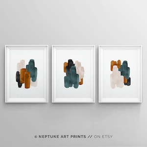 May include: Set of three abstract art prints featuring a modern design with teal, brown, and beige watercolor shapes. The prints are framed in white.
