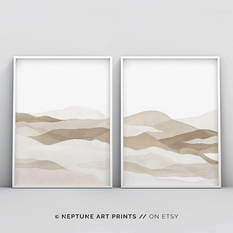 May include: Two framed prints with abstract watercolor landscapes in shades of brown and beige. The prints feature a layered, mountainous design with soft, flowing lines.