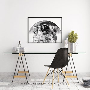 Peut inclure: Une photographie en noir et blanc d'un astronaute en combinaison spatiale, flottant devant la lune. L'astronaute porte un casque et a une expression s&eacute;rieuse sur son visage. La lune est en arri&egrave;re-plan et est partiellement masqu&eacute;e par le corps de l'astronaute.