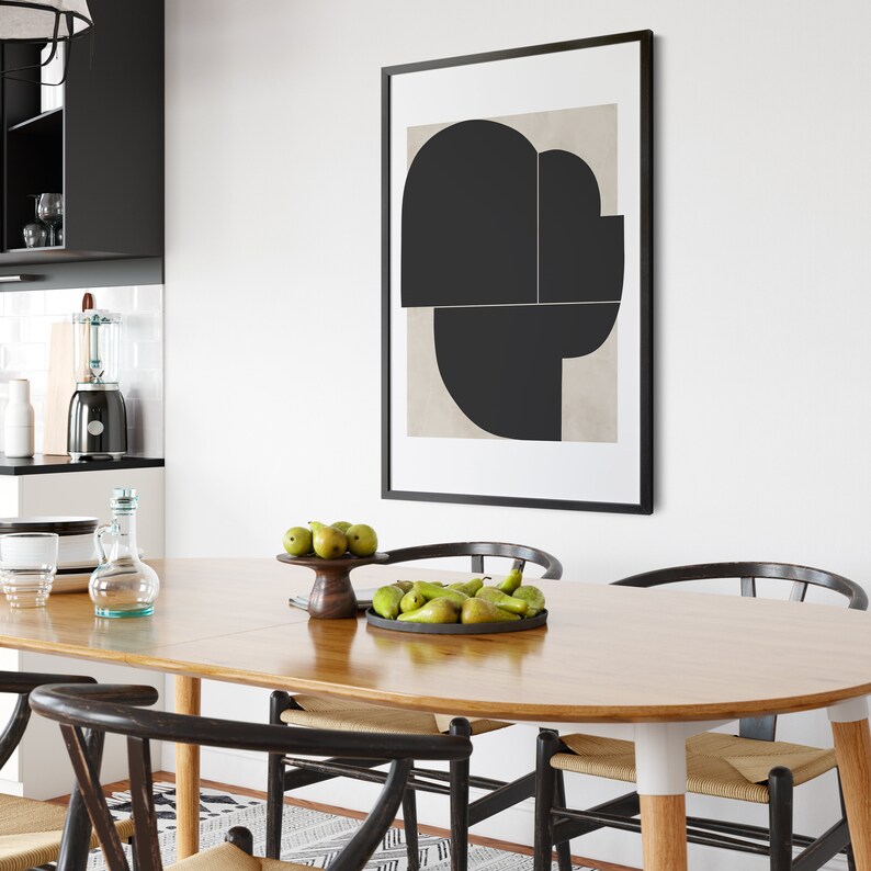 May include: A wooden dining table with a light wood finish and a black framed abstract art print above it. The table is set with a bowl of green pears and a wooden bowl with pears.