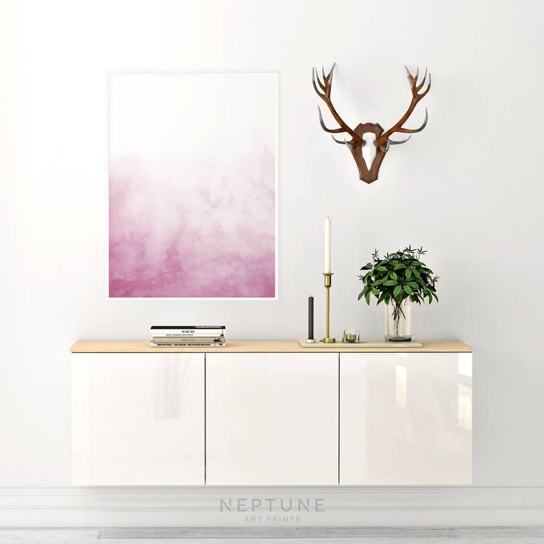 May include: White cabinet with three doors, a pink watercolor print, a wooden deer head mounted on the wall, and a vase with green plants on top of the cabinet.