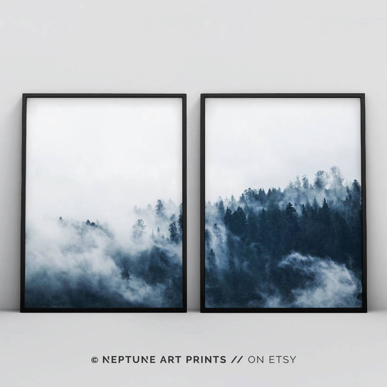 May include: Two framed prints of a misty forest scene in shades of blue. The top of the trees are visible above the fog.
