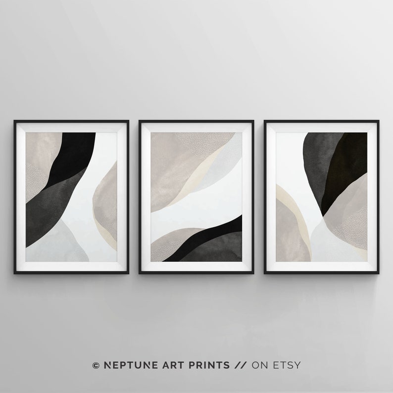 May include: Set of three abstract art prints featuring black and white shapes on a light gray background. The prints are framed in black frames.