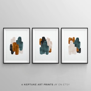 May include: Set of three abstract art prints featuring a modern design with teal, brown, and beige watercolor shapes. The prints are framed in black frames and hung on a white wall.