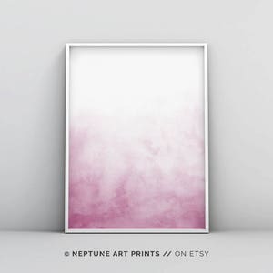 May include: A framed watercolor print with a pink ombre effect, fading from a darker pink at the bottom to a lighter pink at the top. The print is in a white frame.