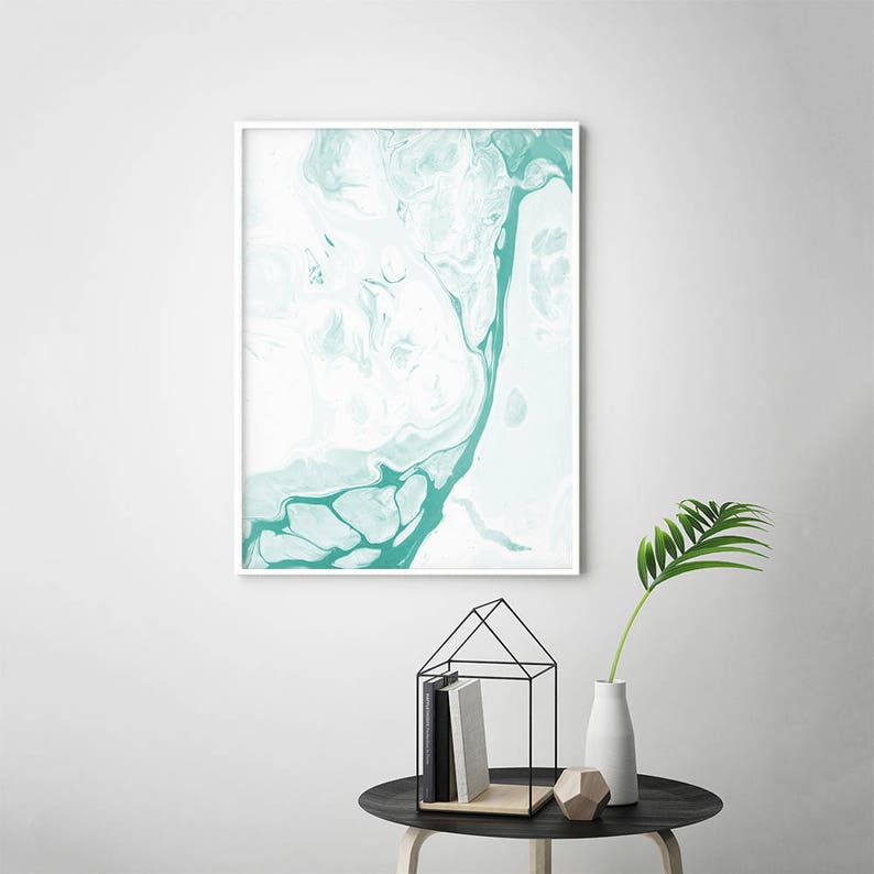 May include: Abstract art print with a white background and teal blue marbling. The print is framed in a white frame.