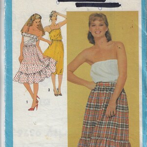May include: Simplicity sewing pattern number 9576 for a skirt. The pattern includes two skirt styles: one with polka dots and a ruffle, and one with a plaid pattern and a lace trim.