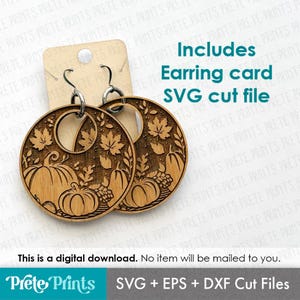 May include: Wooden laser-cut earrings with a fall theme. The earrings feature pumpkins, leaves, and grapes. The text "Includes Earring card SVG cut file" is visible. The earrings are attached to a cardboard earring card.