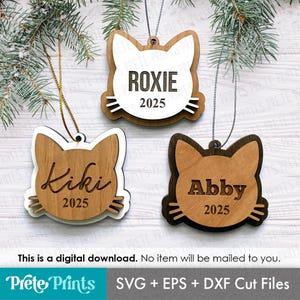 May include: Three wooden cat-shaped ornaments, each with a name and the year 2025. The ornaments are brown and white, featuring names such as "Roxie," "Kiki," and "Abby." They are designed for digital download.