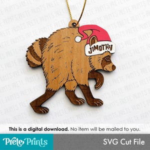 May include: A wooden raccoon ornament featuring a red Santa hat with the name JIMOTHY printed in black on the white brim. The raccoon is brown with a striped tail and is suspended by a gold string. The text This is a digital download is visible.