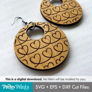 May include: Wooden heart-shaped earrings with a laser-cut design. The earrings are round with a heart pattern and a small hole in the center. The earrings are light brown and have a silver hook. The image also contains the text: "This is a digital download. No item will be mailed to you."