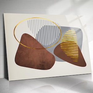 May include: Abstract art print with geometric shapes in brown, grey, and gold on a cream background. A gold oval and gold striped shapes are prominent. The artwork is displayed on a white surface.